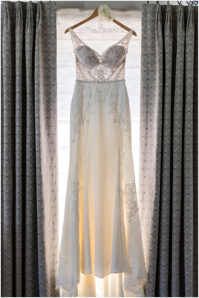 lace bridal gown hanging in window with custom name hanger