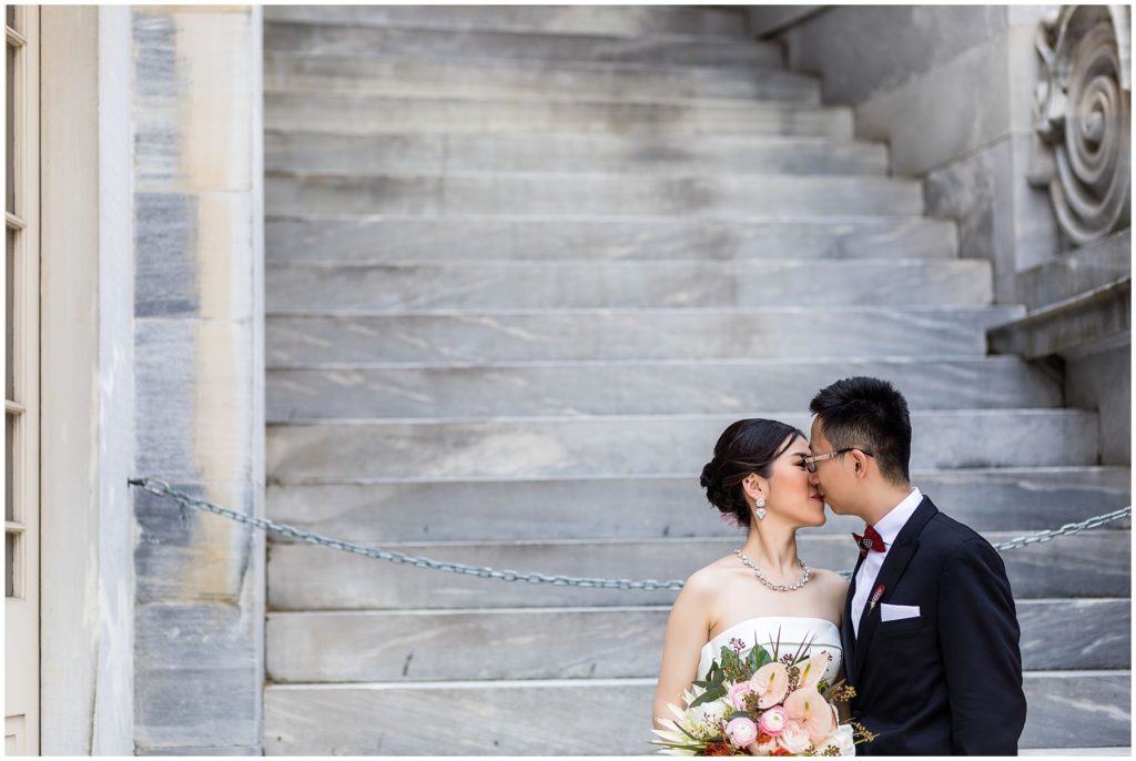 bride and groom kissing on marble staircase