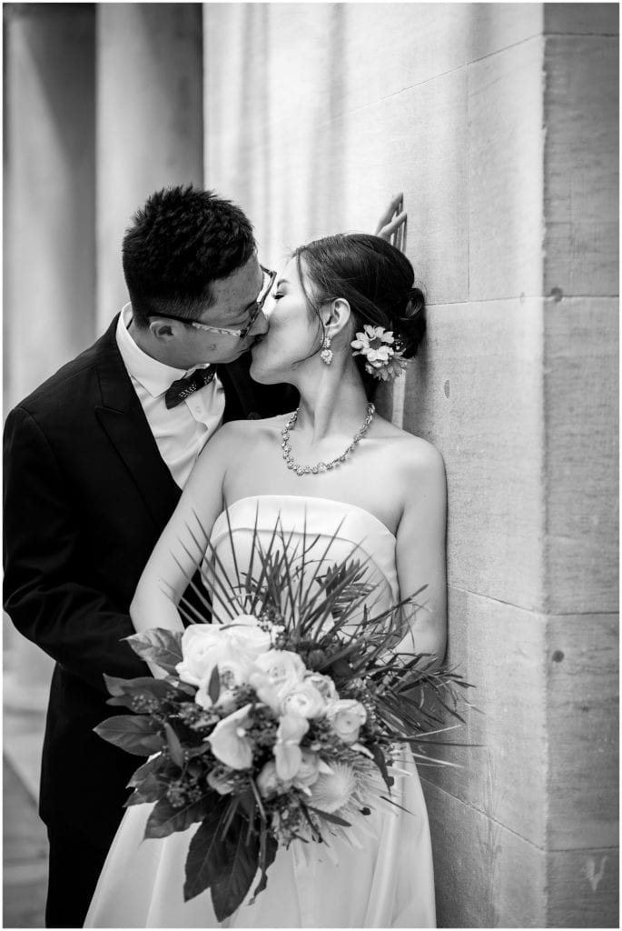 black and white romantic and intimate bride and groom portrait leaning against marble building
