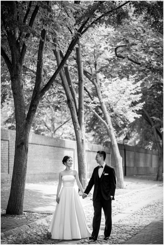 black and white romantic bride and groom portrait walking down old cobblestone road