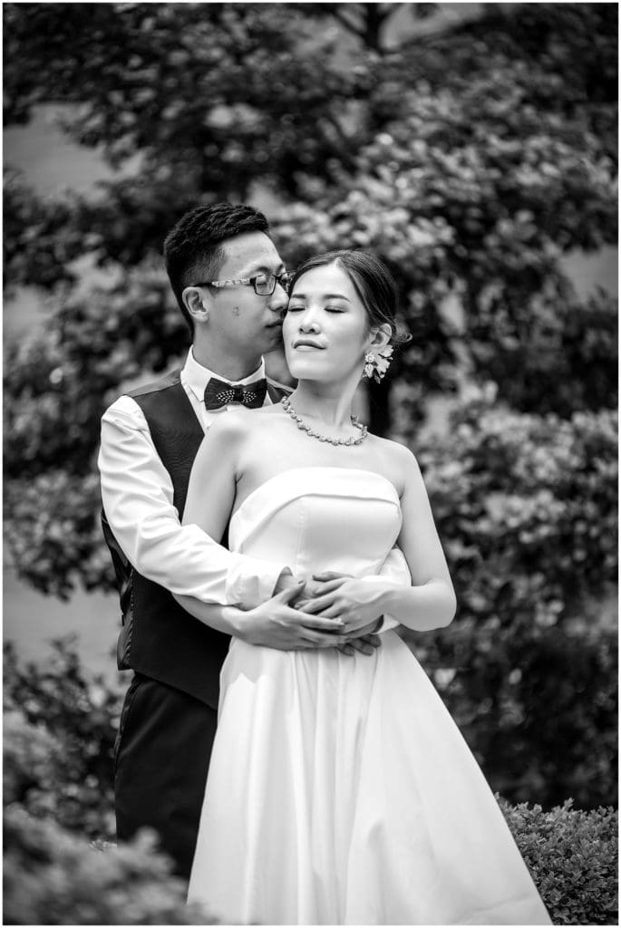 black and white affectionate bride and groom kissing on the cheek portrait