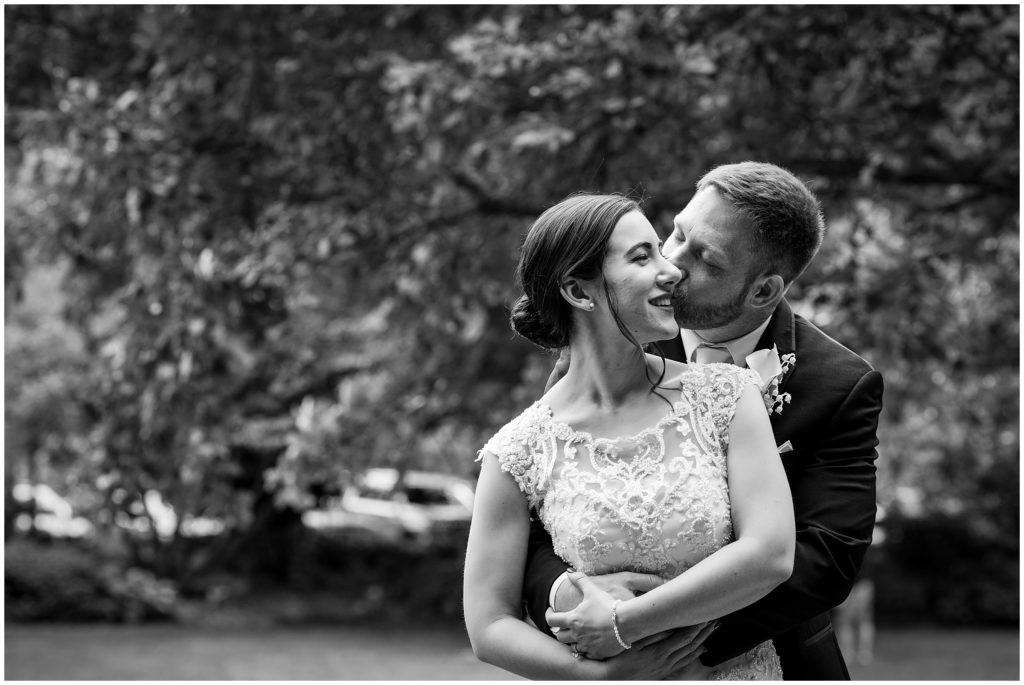 romantic outdoor portrait of groom kissing bride's cheek