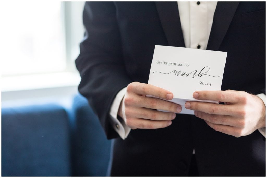 detail of groom reading his card from his bride at the Cambria Hotel ahead of their wedding at the Lucy by Cescaphe