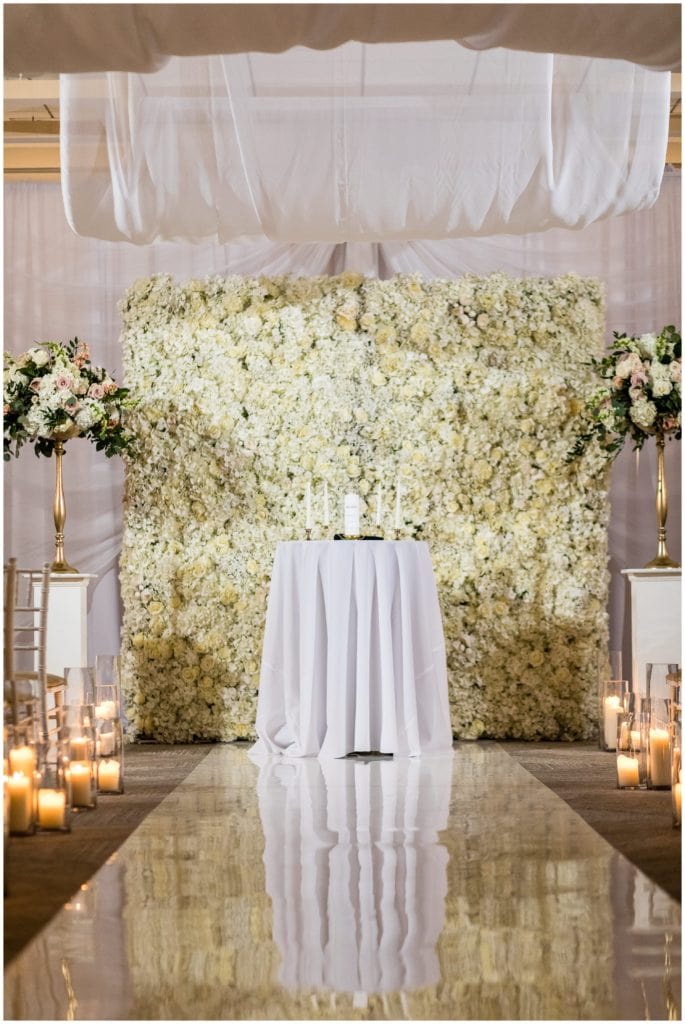 Gorgeous draped ceremony room with white flower wall at the Lucy by Cescaphe