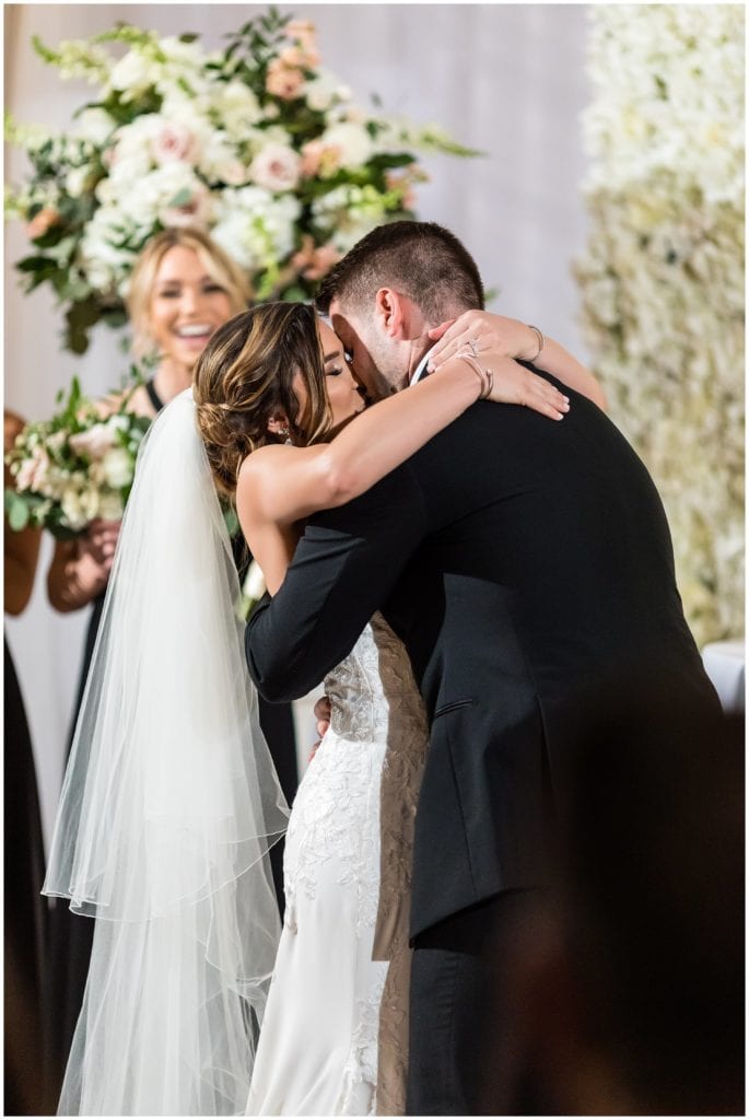 Bride and groom share a kiss during their wedding ceremony at The Lucy by Cescaphe