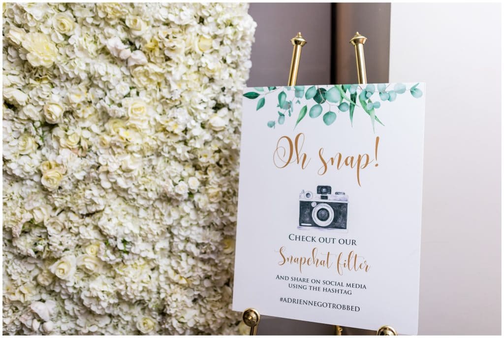 snapchat filter and wedding hashtag sign with floral wall