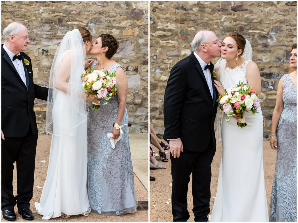 bride receiving a kiss from her parents before giving her away