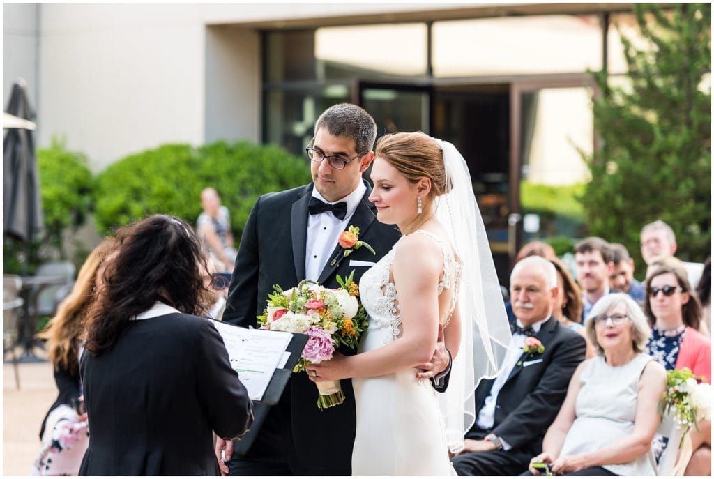 bride and groom during their outdoor wedding ceremony as grooms father looks on