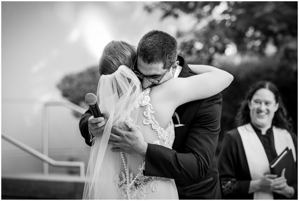 black and white portrait of groom tearfully hugging his bride after his vows