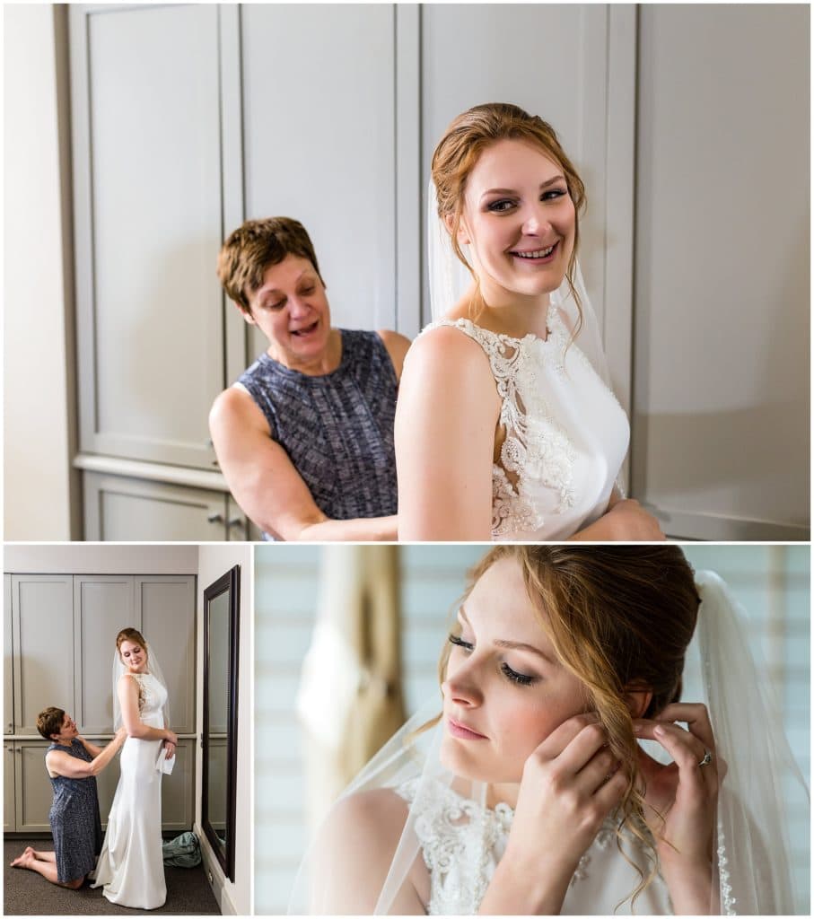 Mother of the bride buttoning bride's dress, bride putting on her earrings