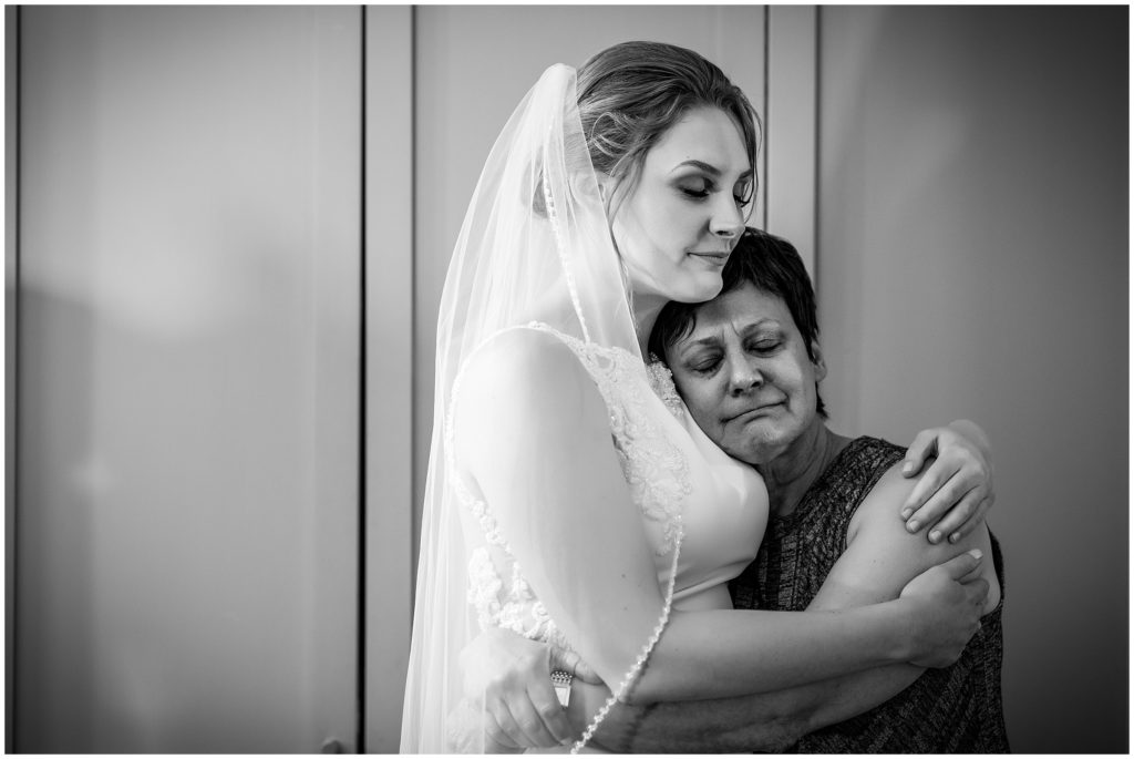 black and white portrait of bride hugging her emotional mother