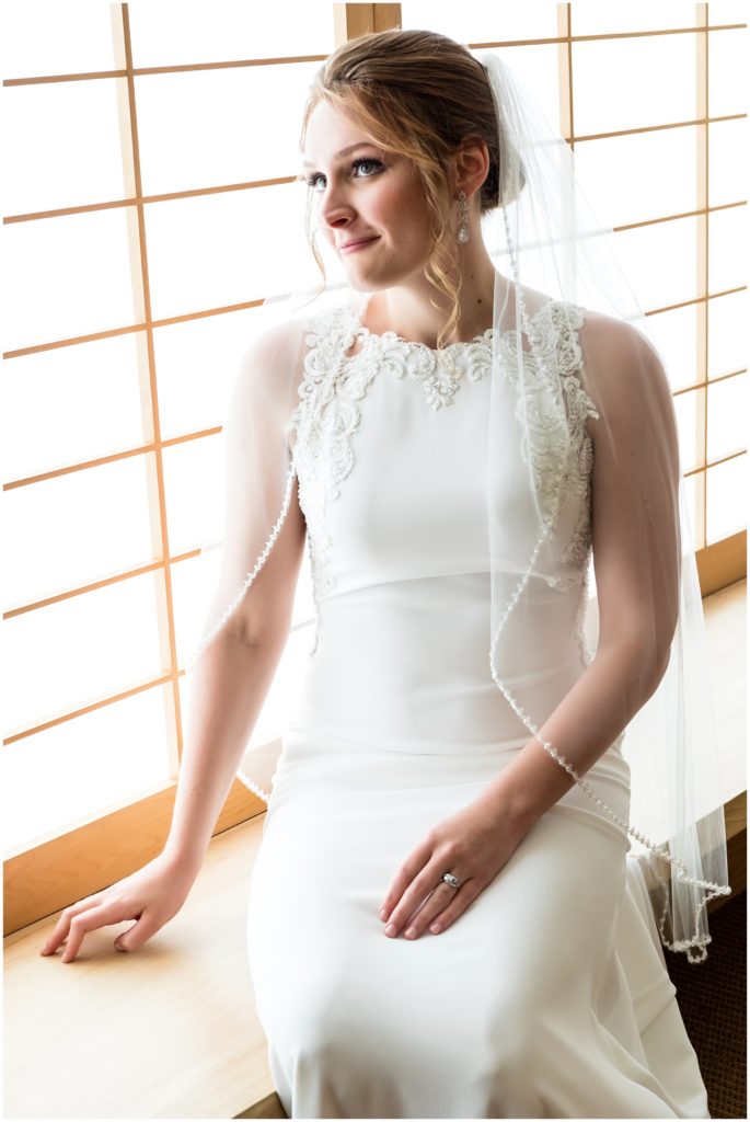 Window lit portrait of bride sitting on window seat