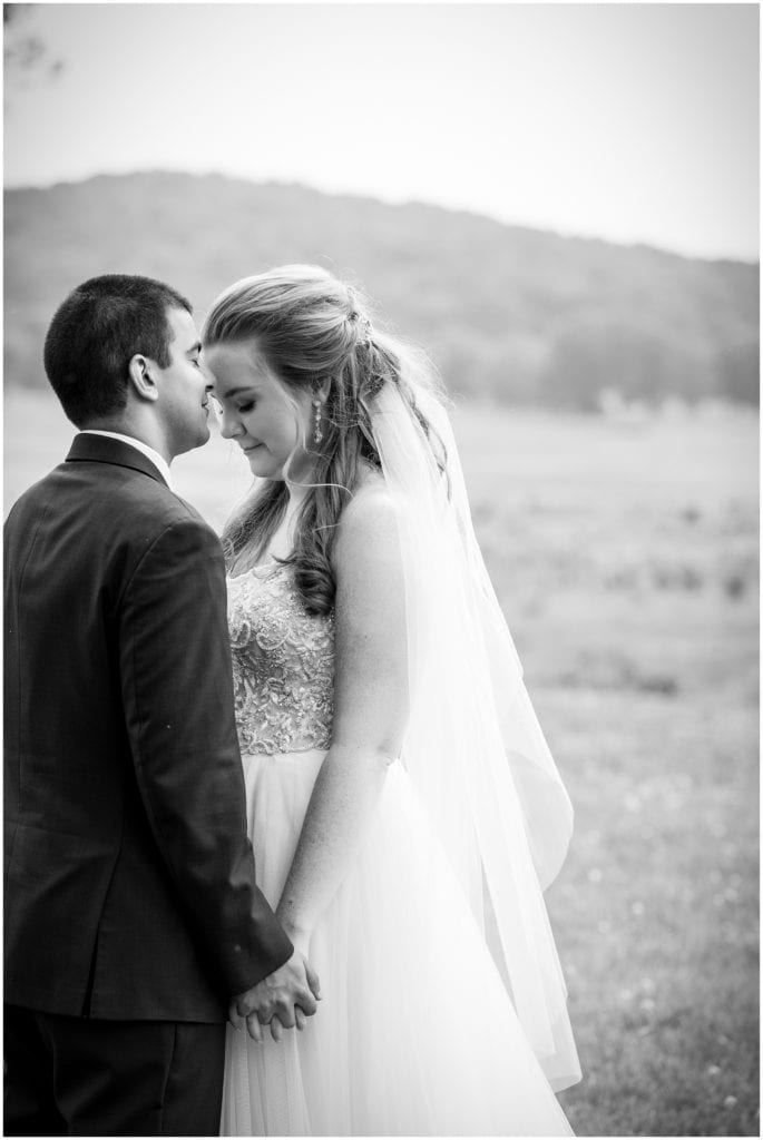 intimate black and white portrait with groom kissing brides forehead