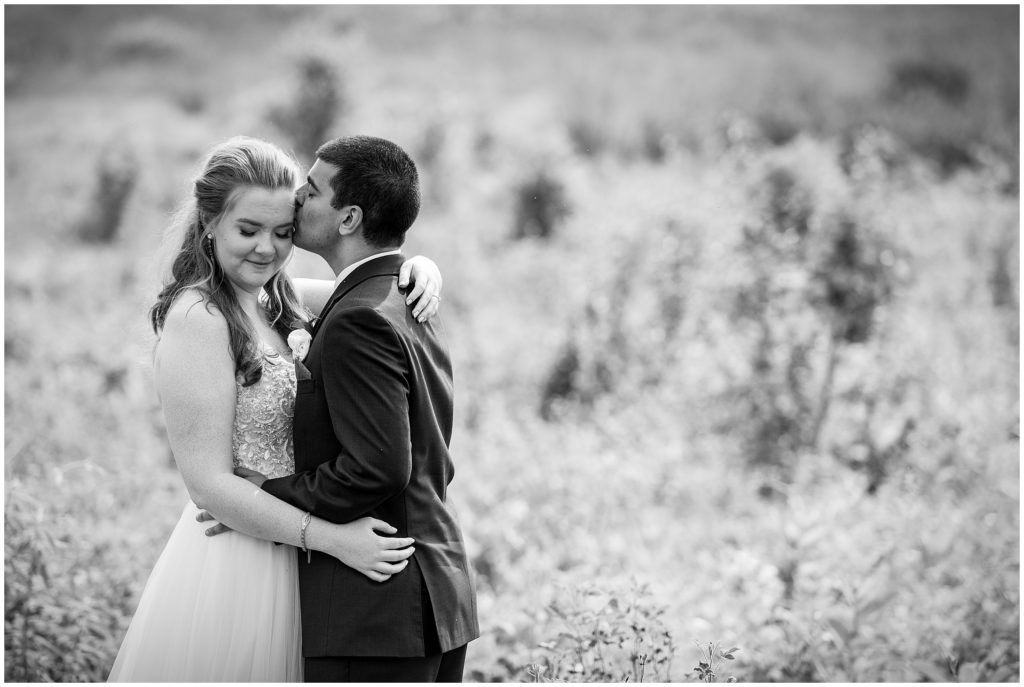 romantic black and white bride and groom portrait with groom embracing bride