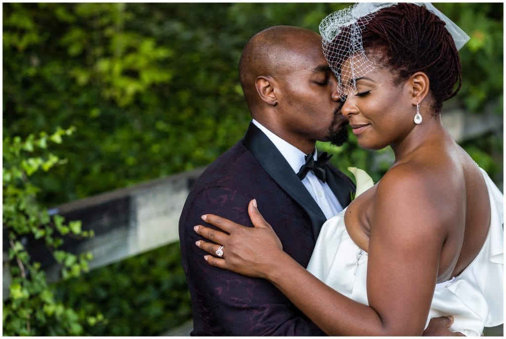 Intimate wedding portrait with groom softly kissing bride on the cheek