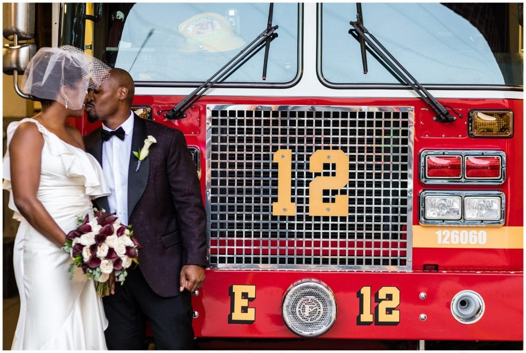 Bride and groom kissing in front of firetruck