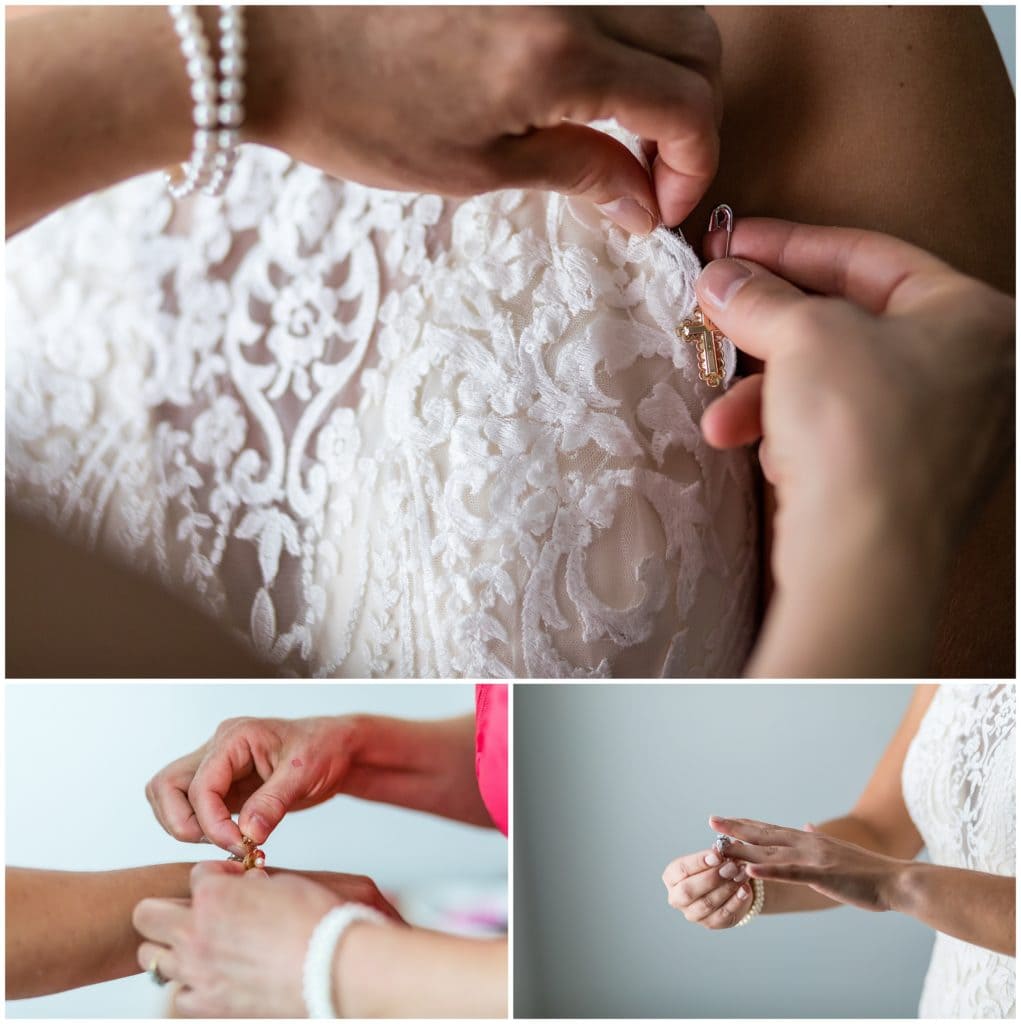 Bride pinning cross charm into her dress and putting on her jewelry