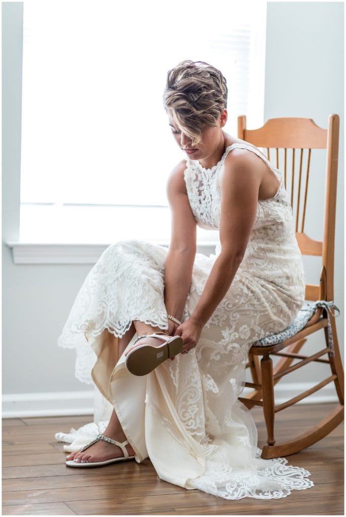 Window lit bridal portrait of bride putting on shoes