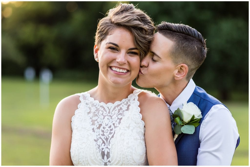 Traditional wedding portrait with brides kissing on the cheek