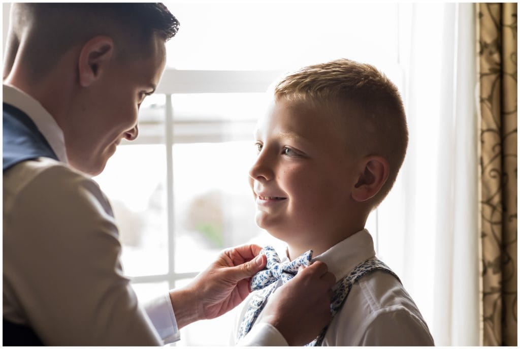 Bride helping ring bearer straighten his matching bow tie