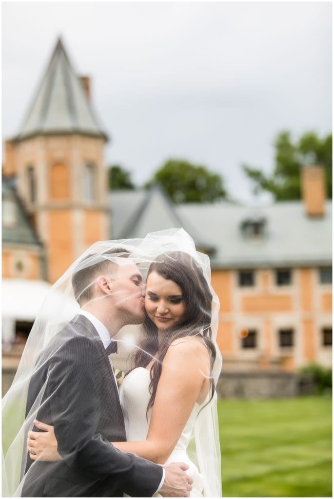 Groom kissing bride on the cheek wedding portrait in front of Cairnwood Estate