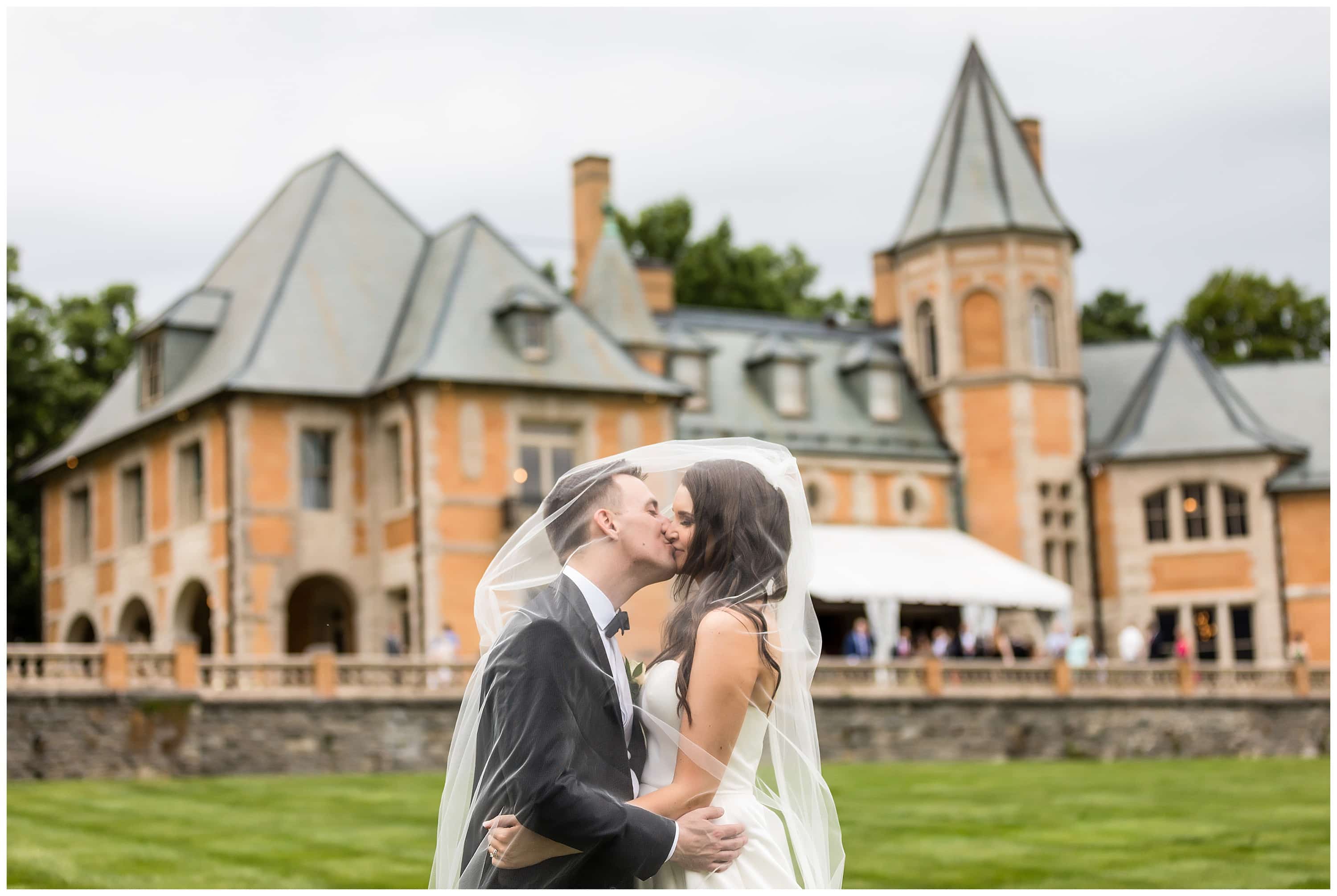 Romantic wedding portrait bride and groom kissing under veil in front of Cairnwood Estate