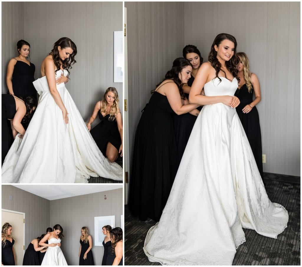 Bridesmaids helping bride into her wedding gown