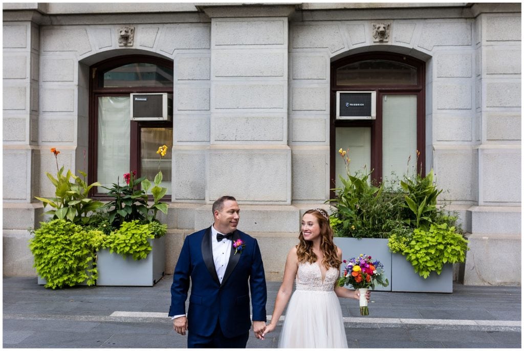Bride and groom walking through City Hall portrait