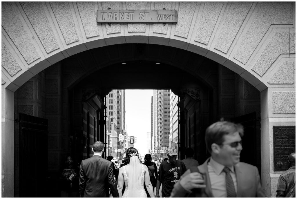 Black and white wedding portrait of bride and groom walking through tunnels at Philadelphia City Hall