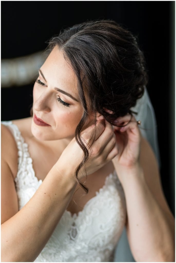 Bridal portrait with bride putting on her earrings