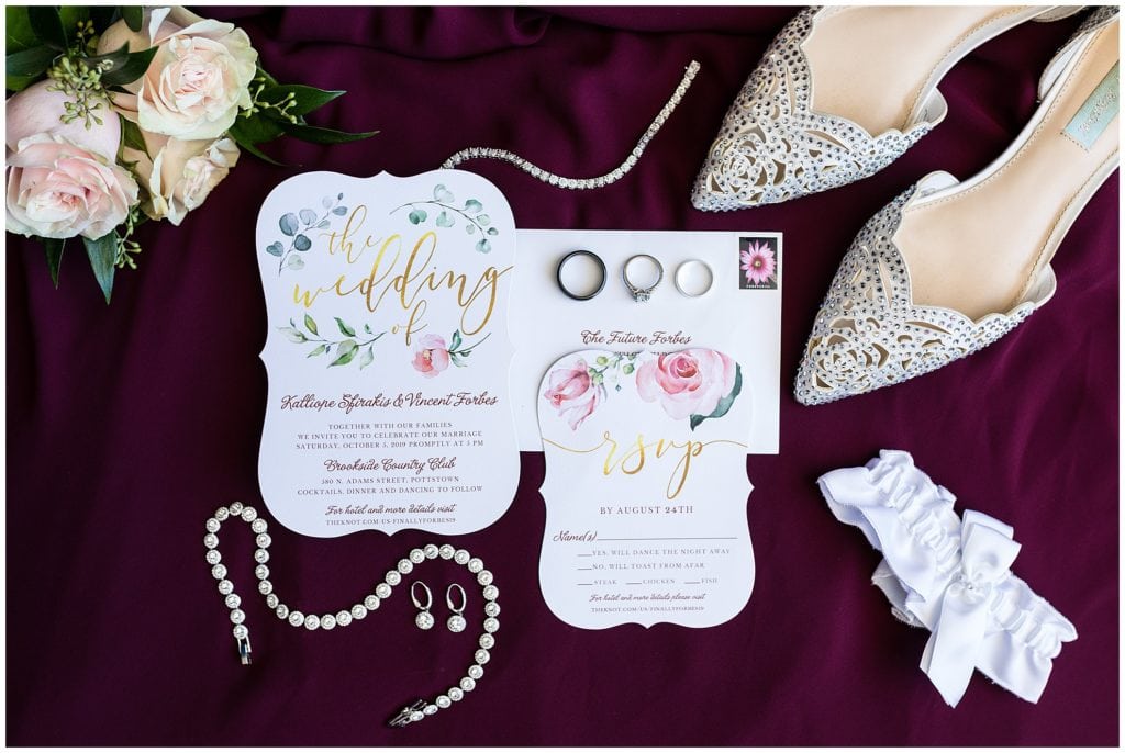 Floral wedding invitation suite with bridal shoes, jewelry, garter, and florals