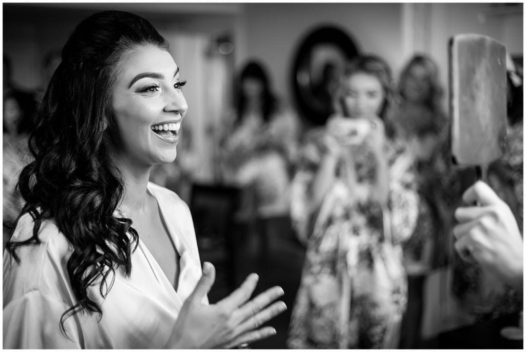 Black and white portrait of bride seeing herself in the mirror on her wedding day