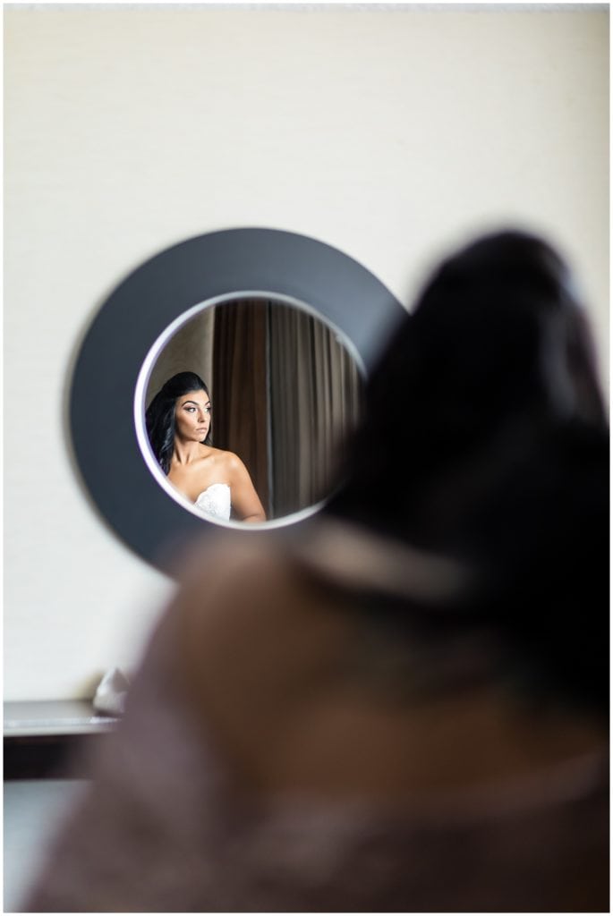 Bride getting ready during prep portrait in small mirror