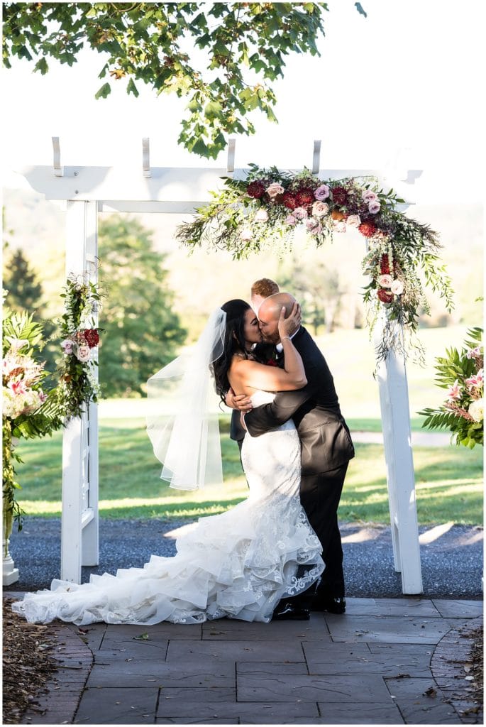 Bride and groom kiss as husband and wife during outdoor wedding ceremony at Brookside Country Club