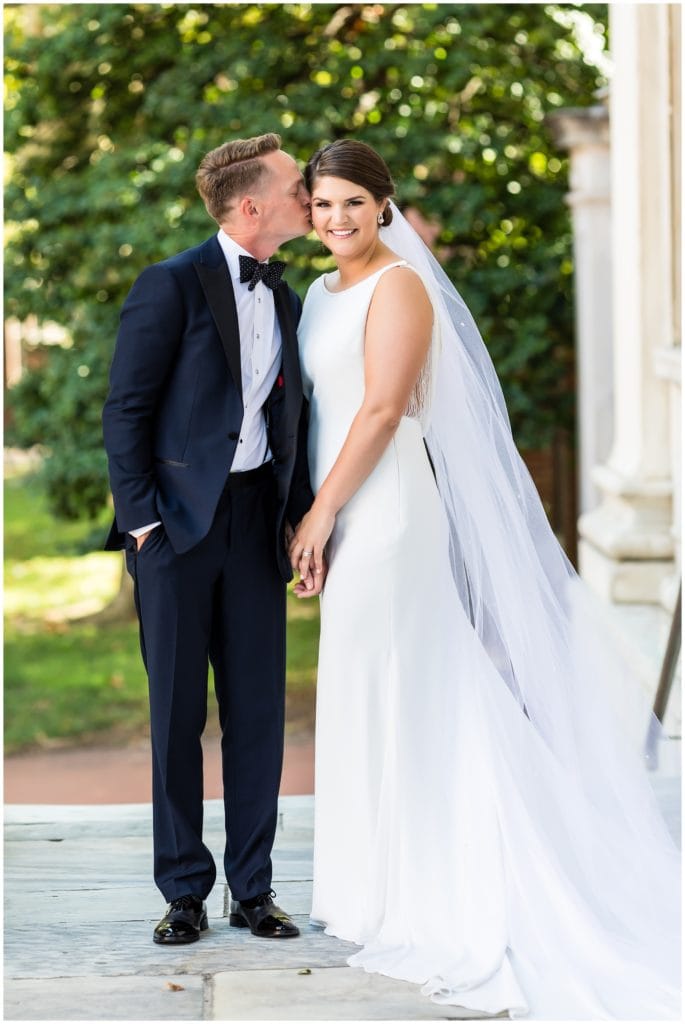 Traditional bride and groom portrait with groom kissing bride on the cheek