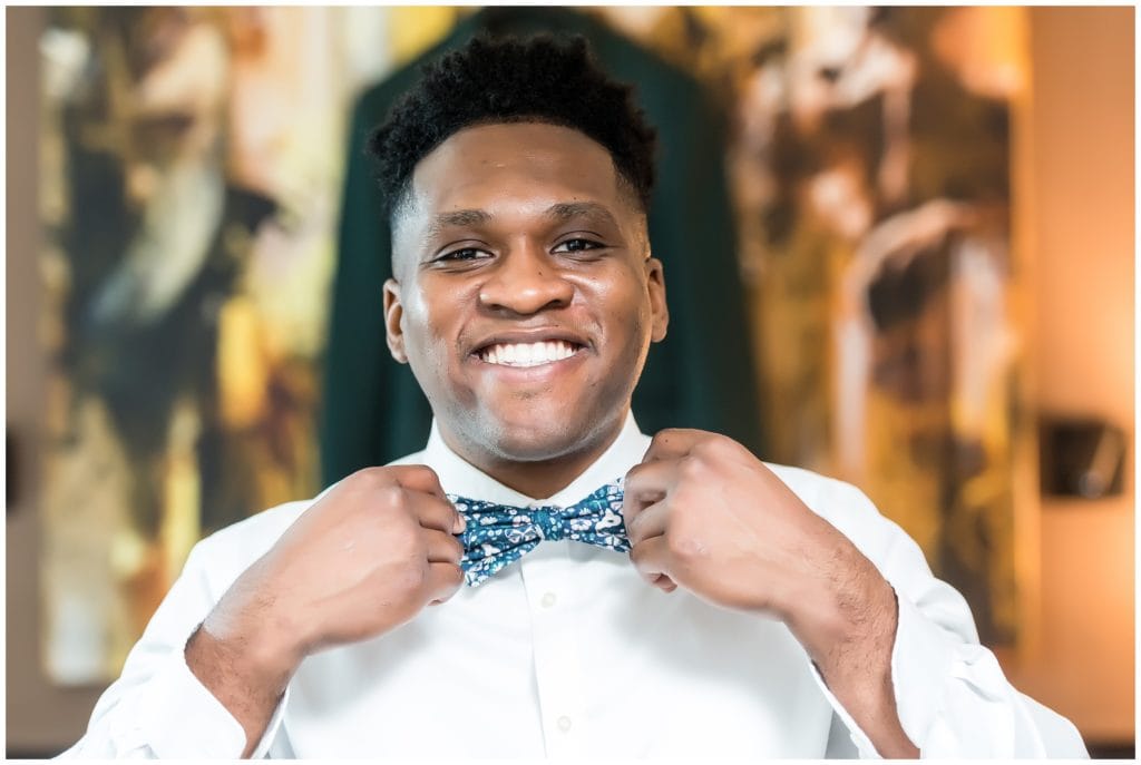 Groom portrait smiling and fixing his bowtie