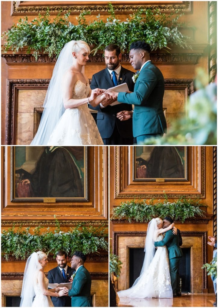 Bride and groom exchanging rings and kissing during wedding ceremony in library at College of Physicians