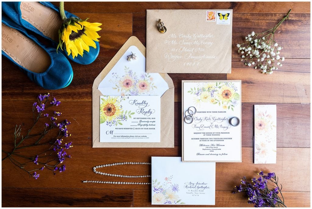 Floral wedding invitation suite with blue shoes, sunflower, purple florals, and wedding jewelry