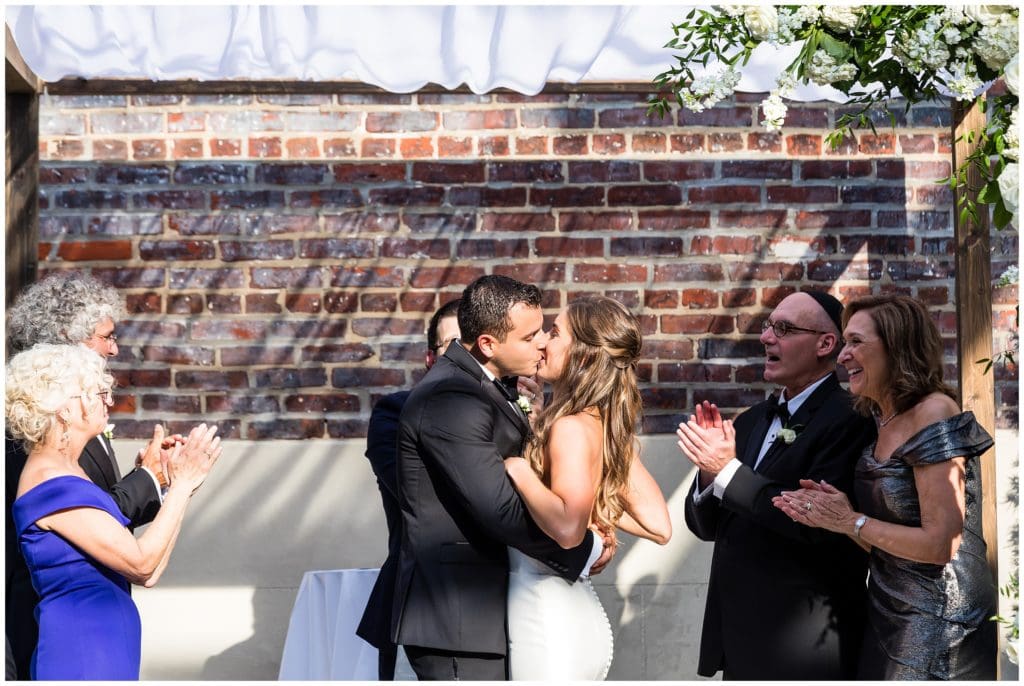 Bride and groom first kiss during Vie Jewish wedding ceremony