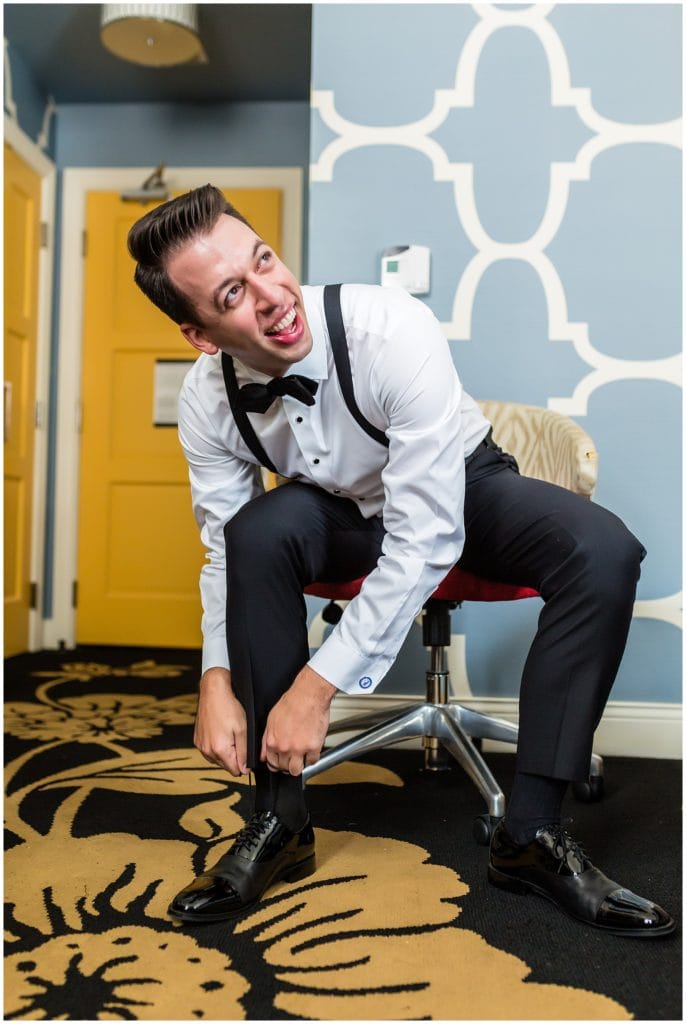 Groom tying his shoe during prep for wedding