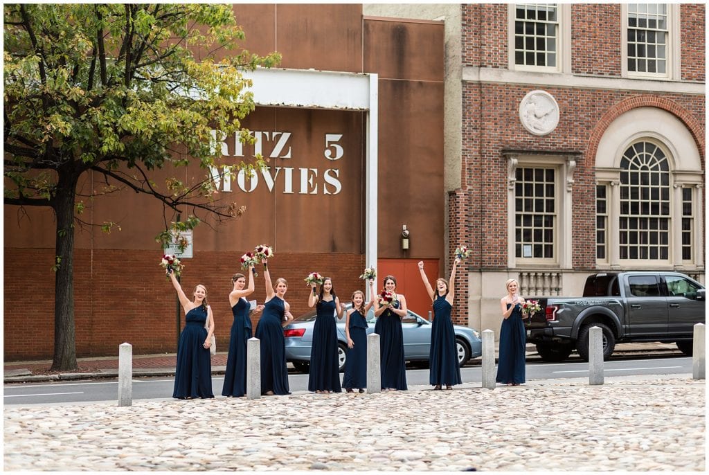 Bridesmaids cheering on bride and groom during portraits from a far at Merchant Exchange Building
