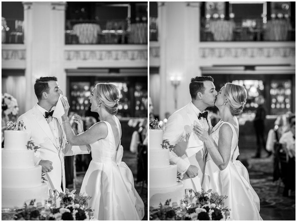 Bride cleans grooms face and kisses him after cake cutting at Ballroom at the Ben wedding reception