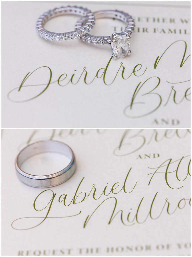 Wedding bands and engagement rings next to bride and grooms name on wedding invitation