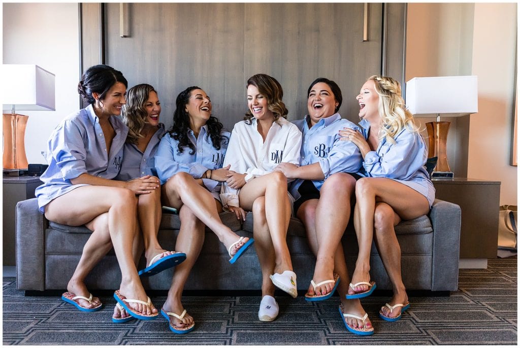 Bride laughing with bridesmaids in matching monogram embroidered shirts