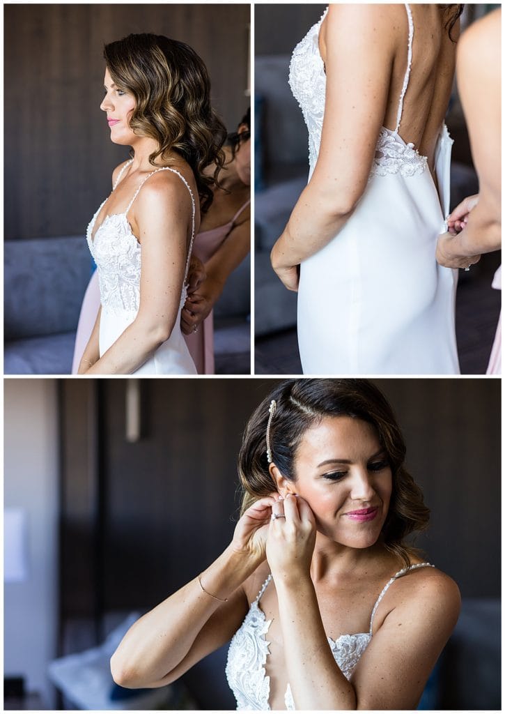 Bridesmaids helping bride into gown and bride putting on her earrings