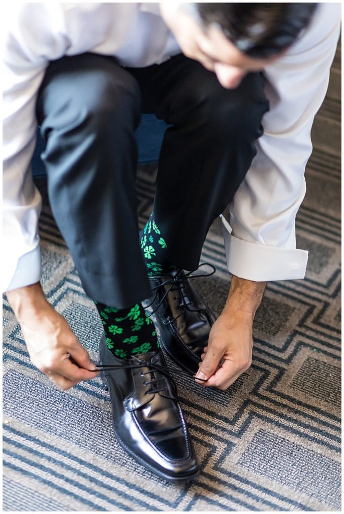 Groom tying his shoe with shamrock sock detail