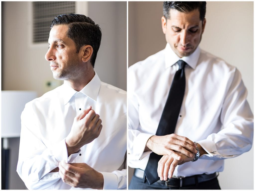 Groom buttoning his shirt and putting on watch wedding prep window lit portraits