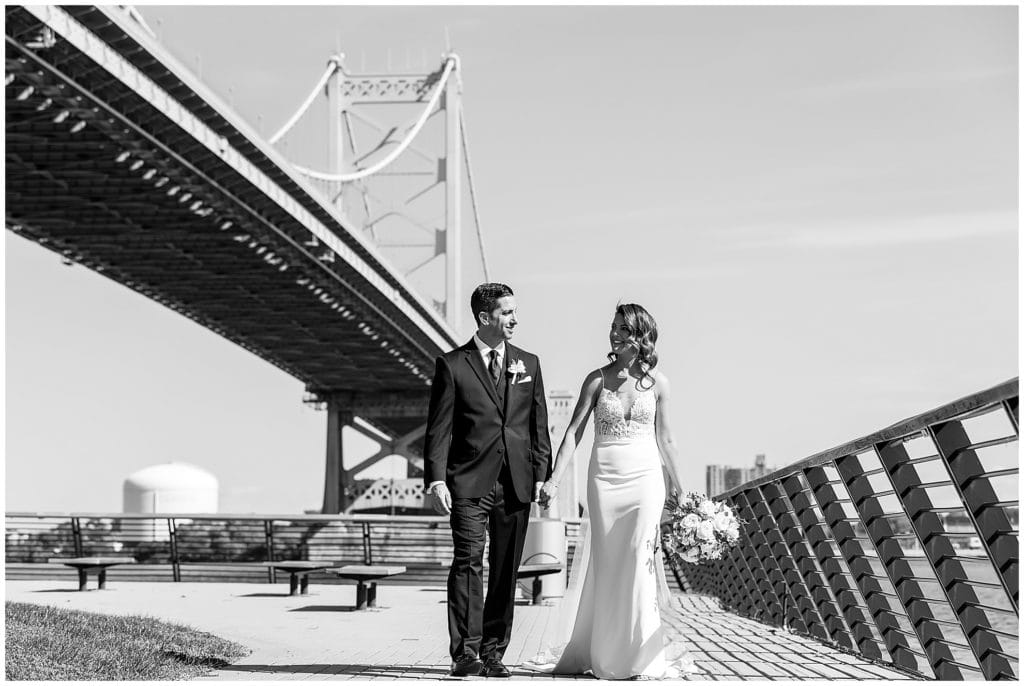 Bride and groom walking on pier next to bride at Race Street Pier Philadelphia wedding portrait