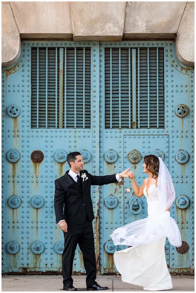 Groom spinning bride in her dress in front of bridge gate in Philadelphia