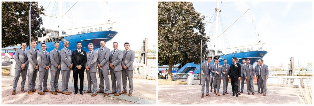 Groomsmen posing and walking on pier in front of boat and wedding venue